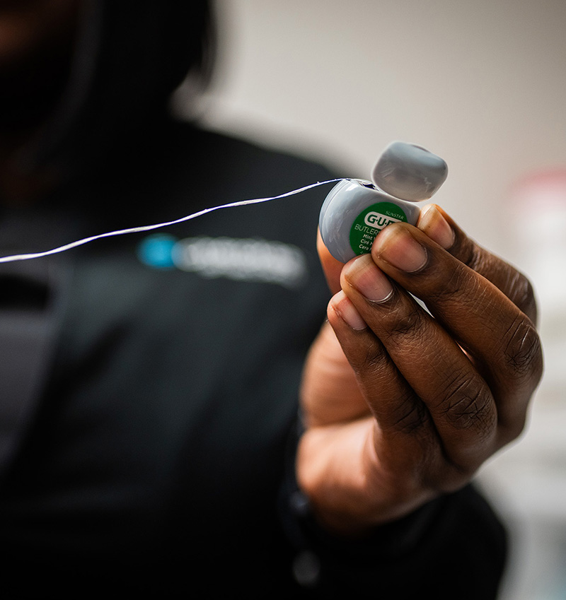 A person holding a pair of headphones with an attached wire, displaying the device against a blurred background.