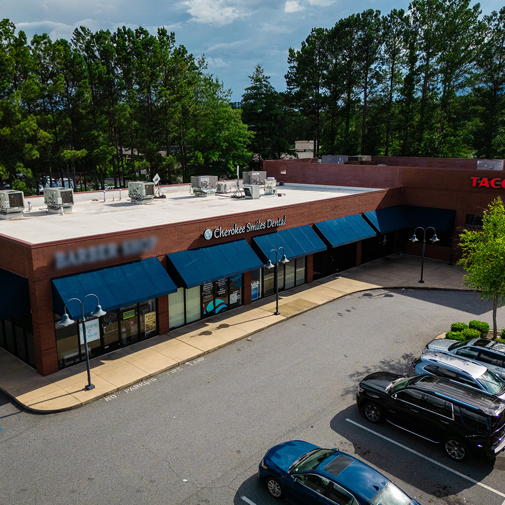 The image shows a commercial building with a parking lot and a sign indicating a business named  Charlie s Bar   Grill.  It appears to be an outdoor scene during daylight, with a clear sky and trees in the background.