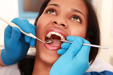The image shows a person receiving dental care from a professional, with visible tools and equipment suggesting a dental procedure being performed.
